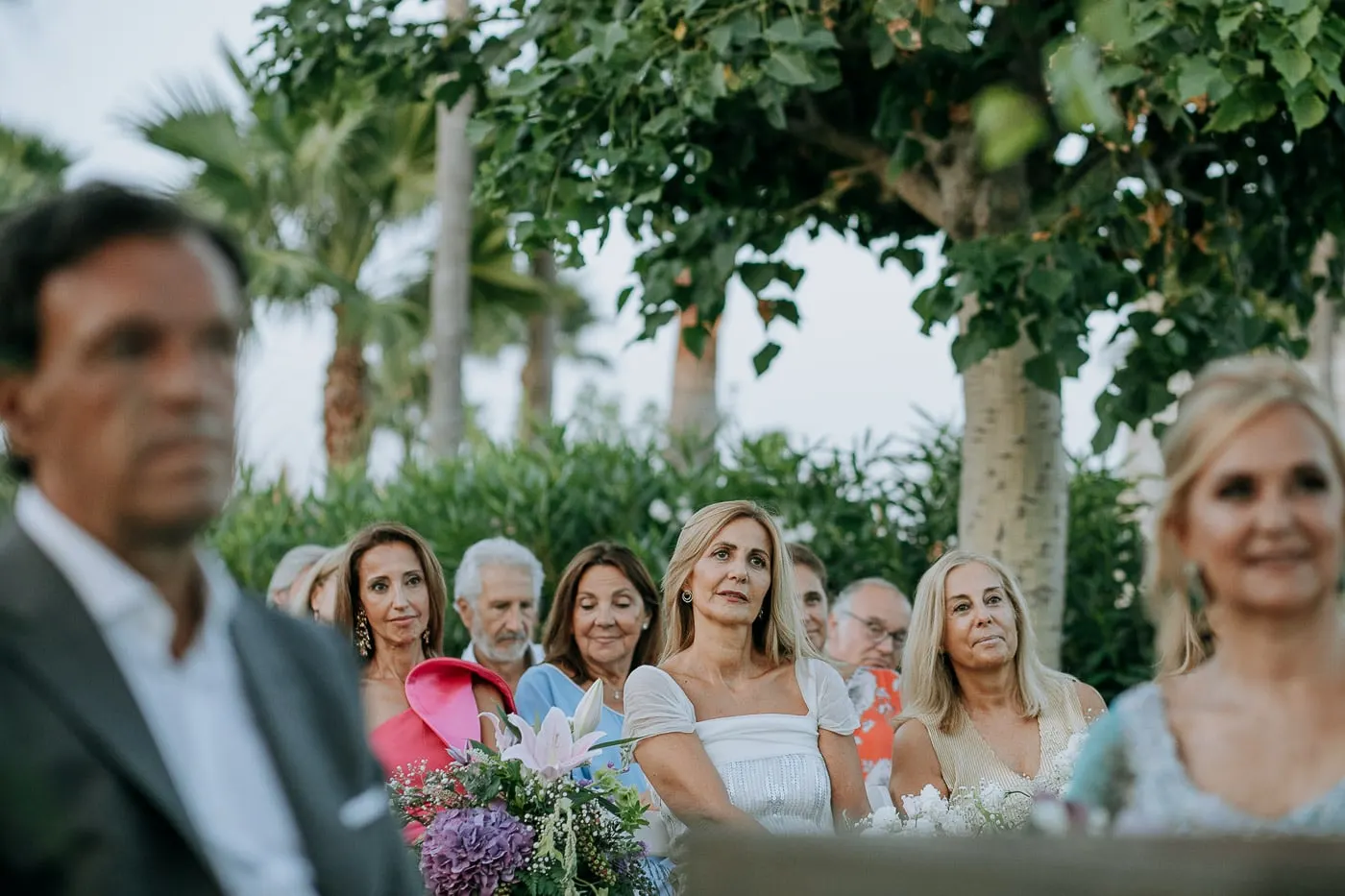 Guests watching the ceremony past the groom's shoulder