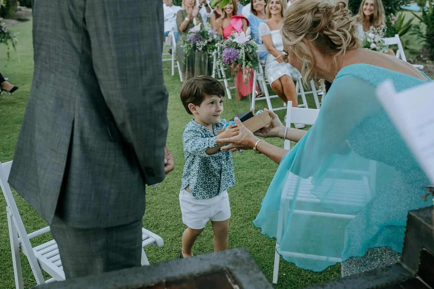 Little boy handing the ring box to the bride