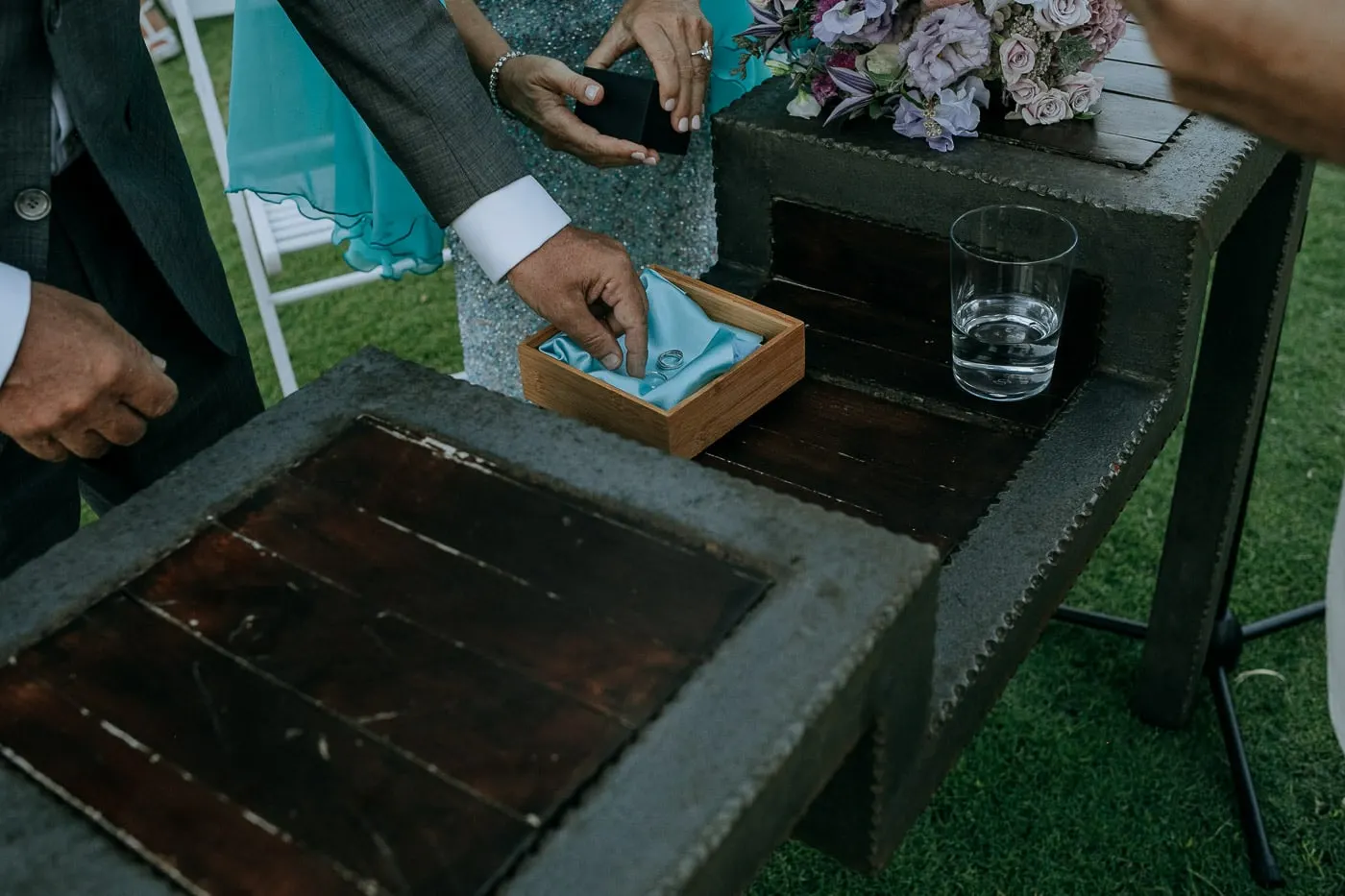 Hands taking the rings from a box lined with turquoise cloth
