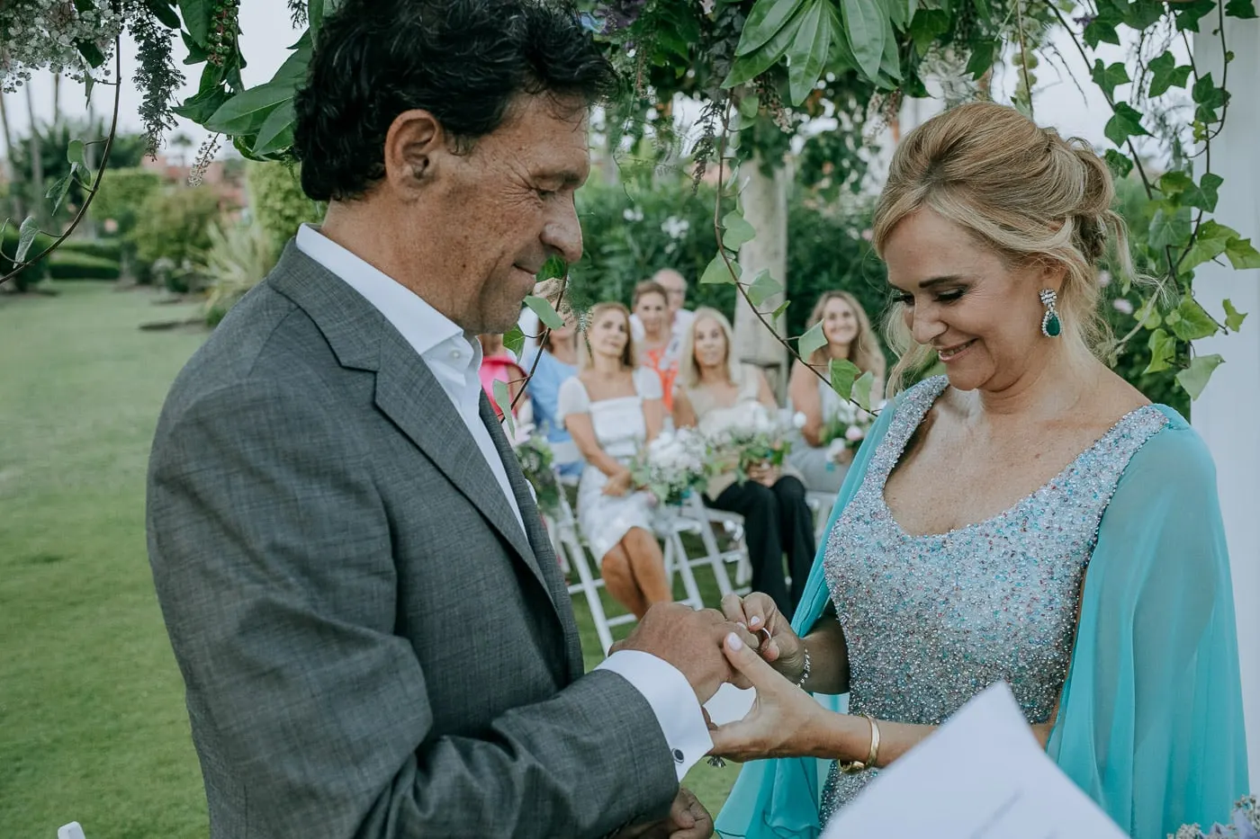 Bride smiling down as the ring goes on