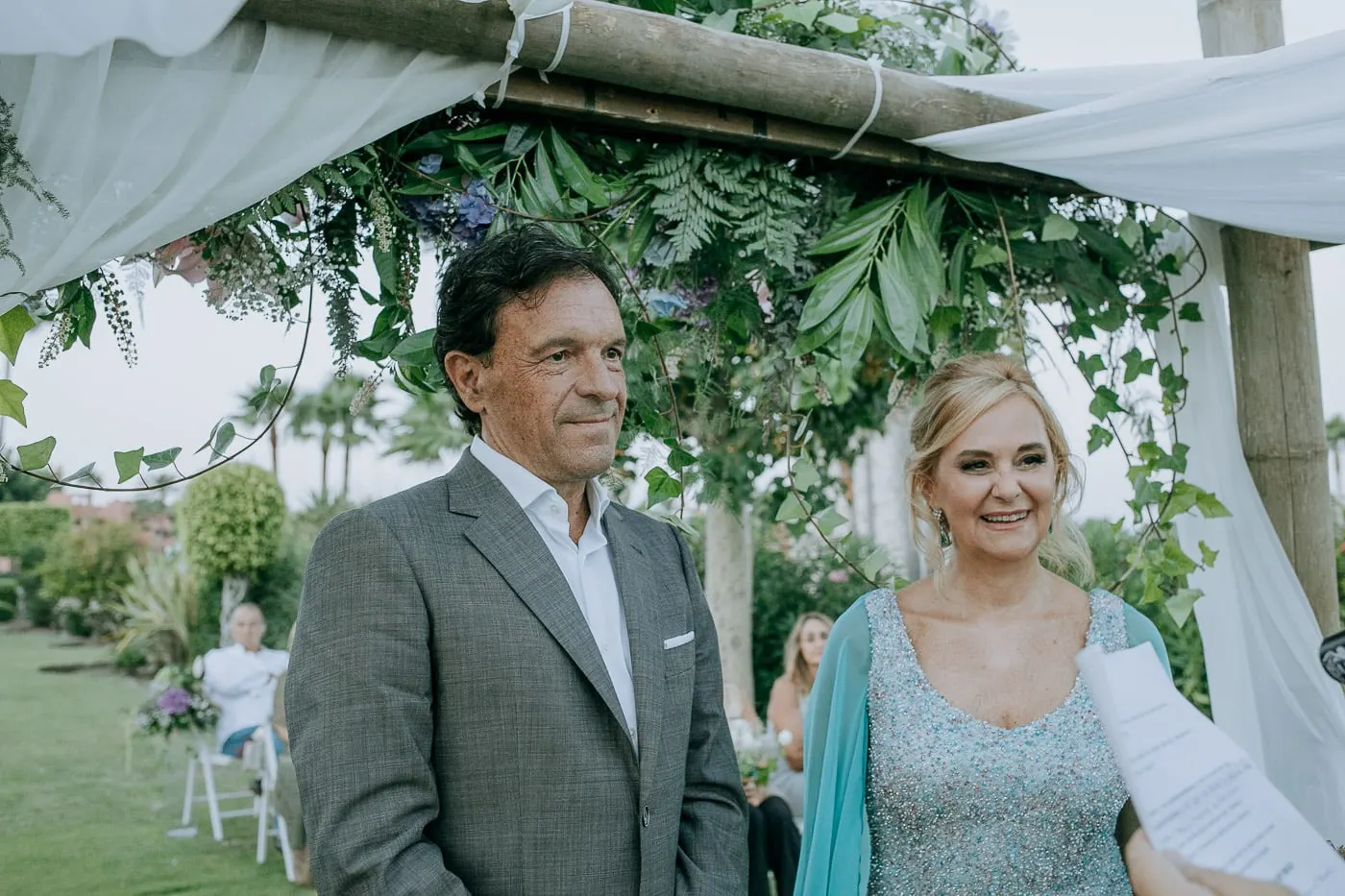 Bride and groom smiling under the arch of greenery