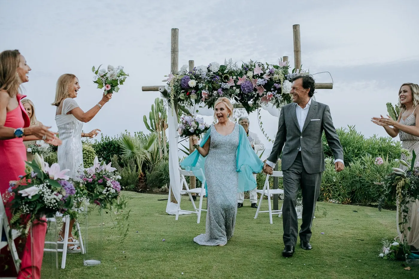 Guests waving bouquets as the couple walk back up the aisle
