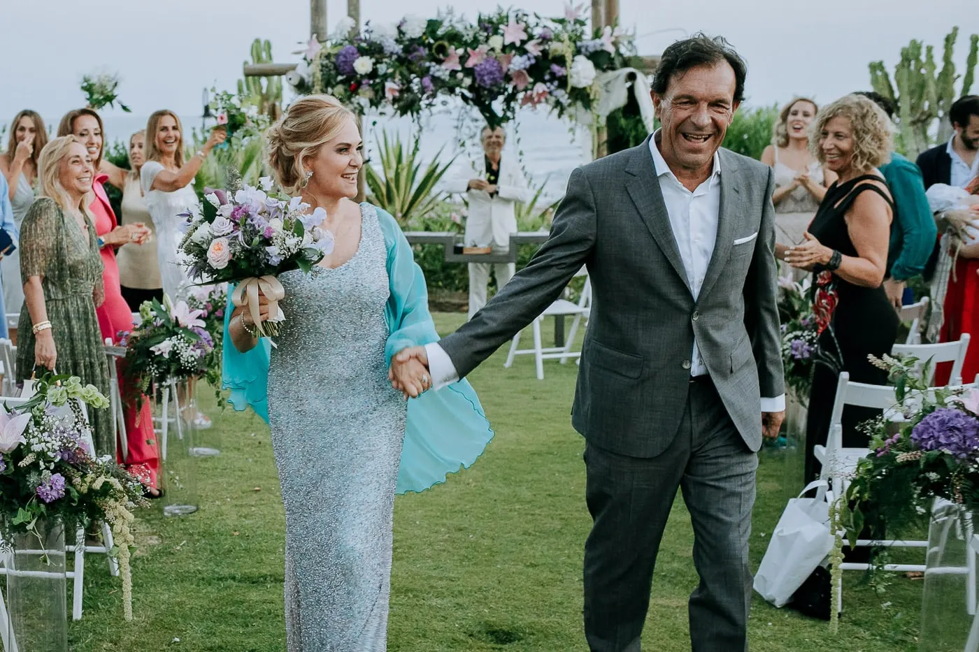 Newlyweds laughing down the aisle among cheering guests, Tikitano