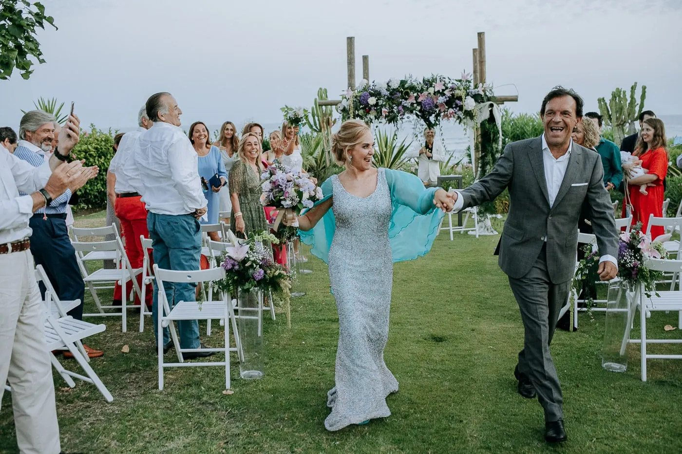 Bride and groom walking out arm in arm past the white chairs