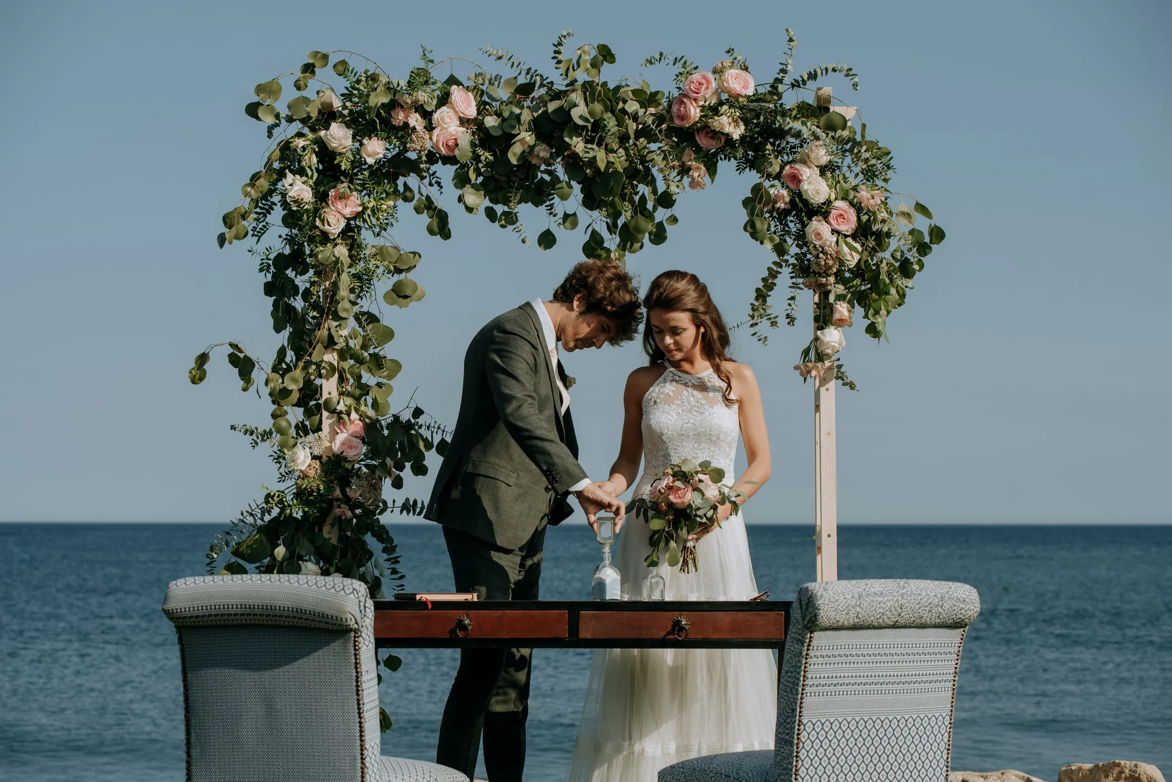 Bride and groom signing at the ceremony table under the flower arch by the sea, Trocadero, Sotogrande