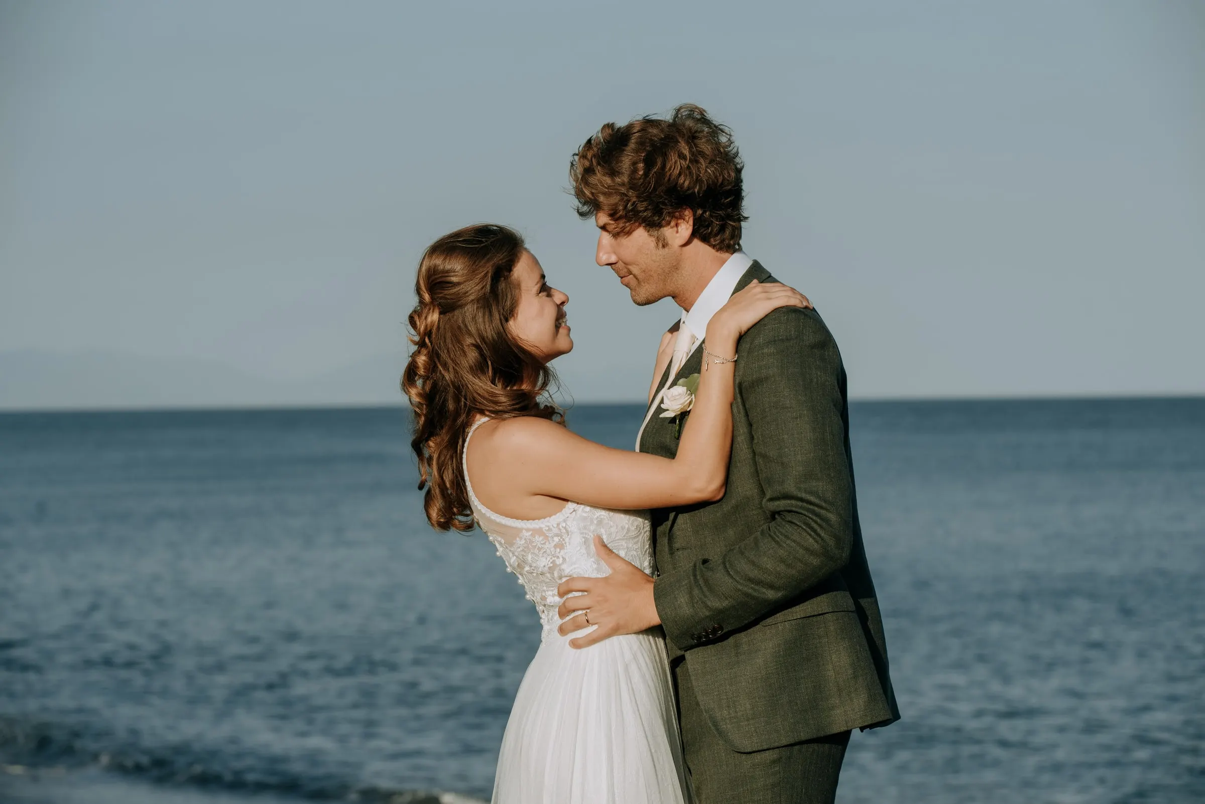 Bride with her arms around the groom's neck, both smiling, with the sea behind, Trocadero, Sotogrande
