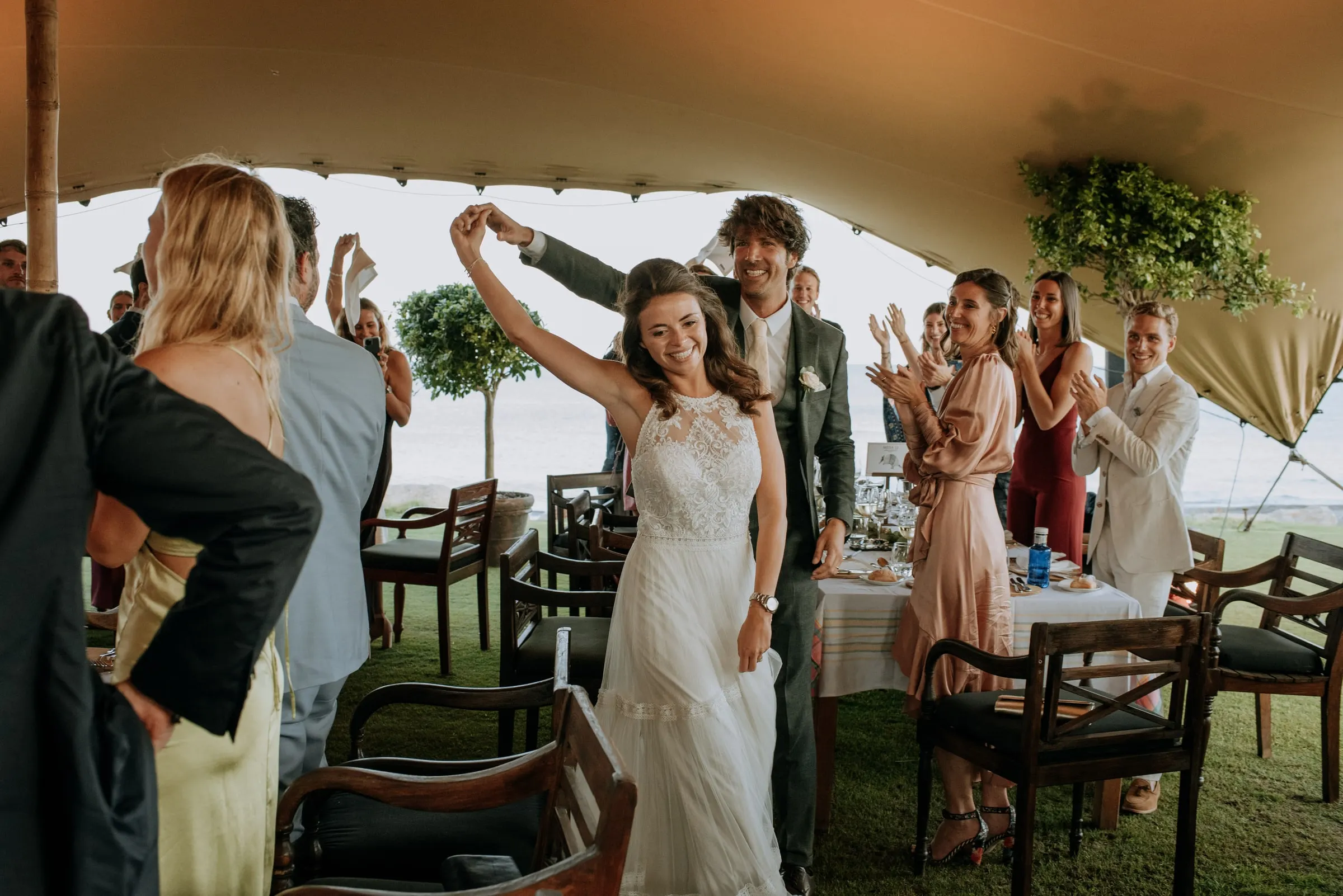 Bride dancing with her arm raised as guests cheer under the reception tent, Trocadero, Sotogrande