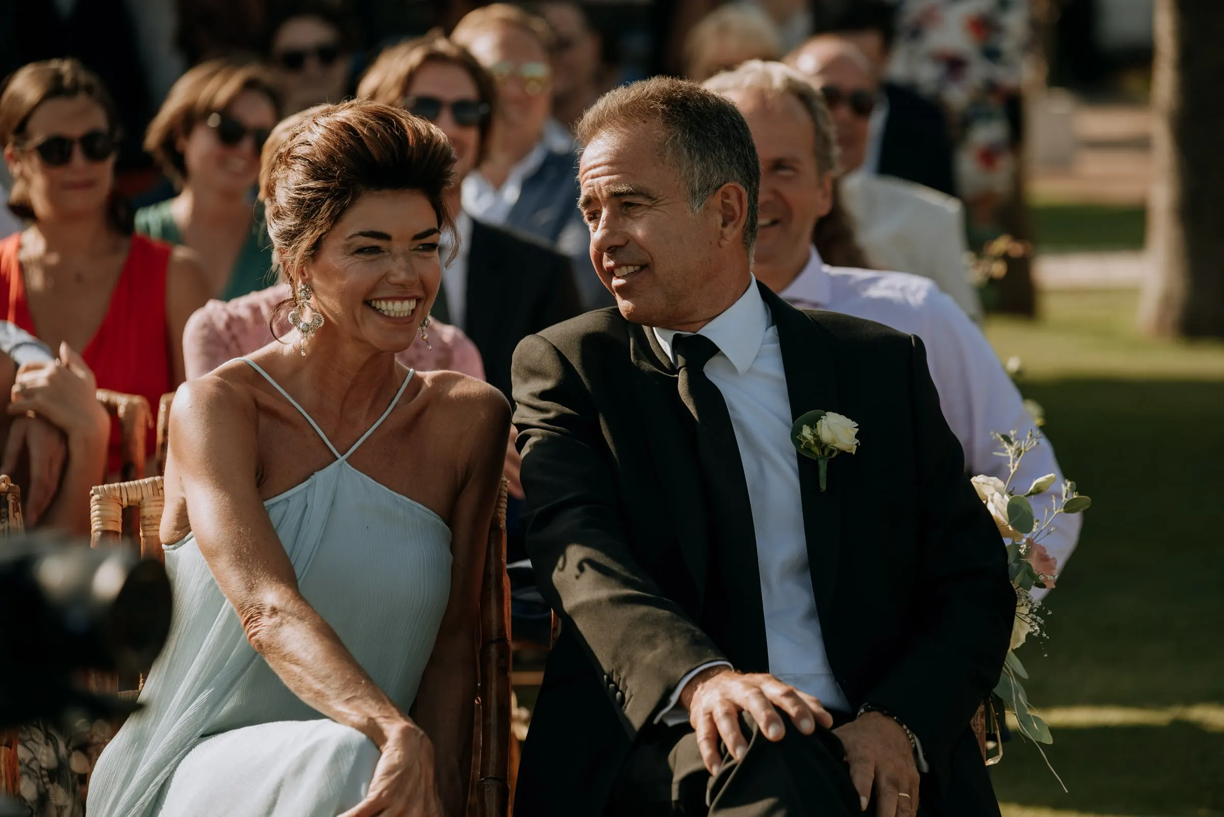 A smiling couple among the guests watching the outdoor ceremony, Trocadero, Sotogrande
