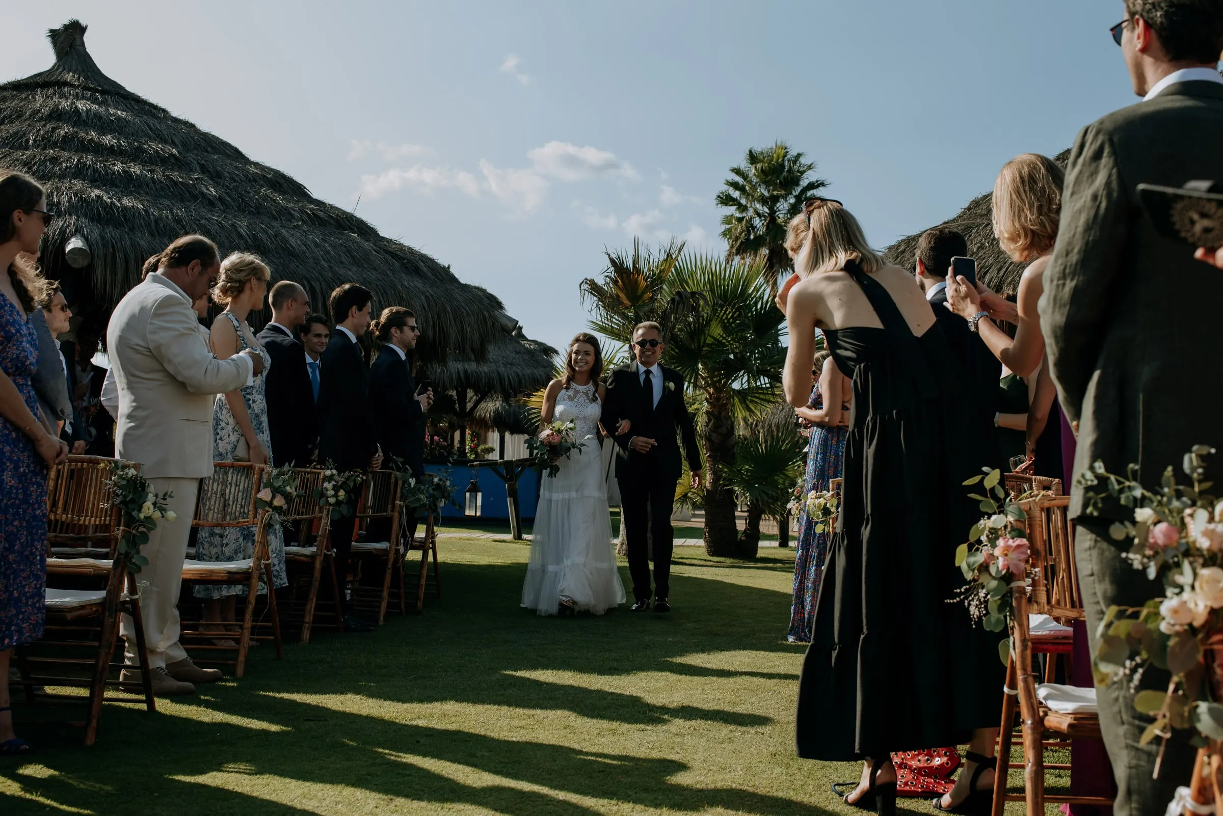 The bride and her father walking down the lawn aisle as guests stand, Trocadero, Sotogrande