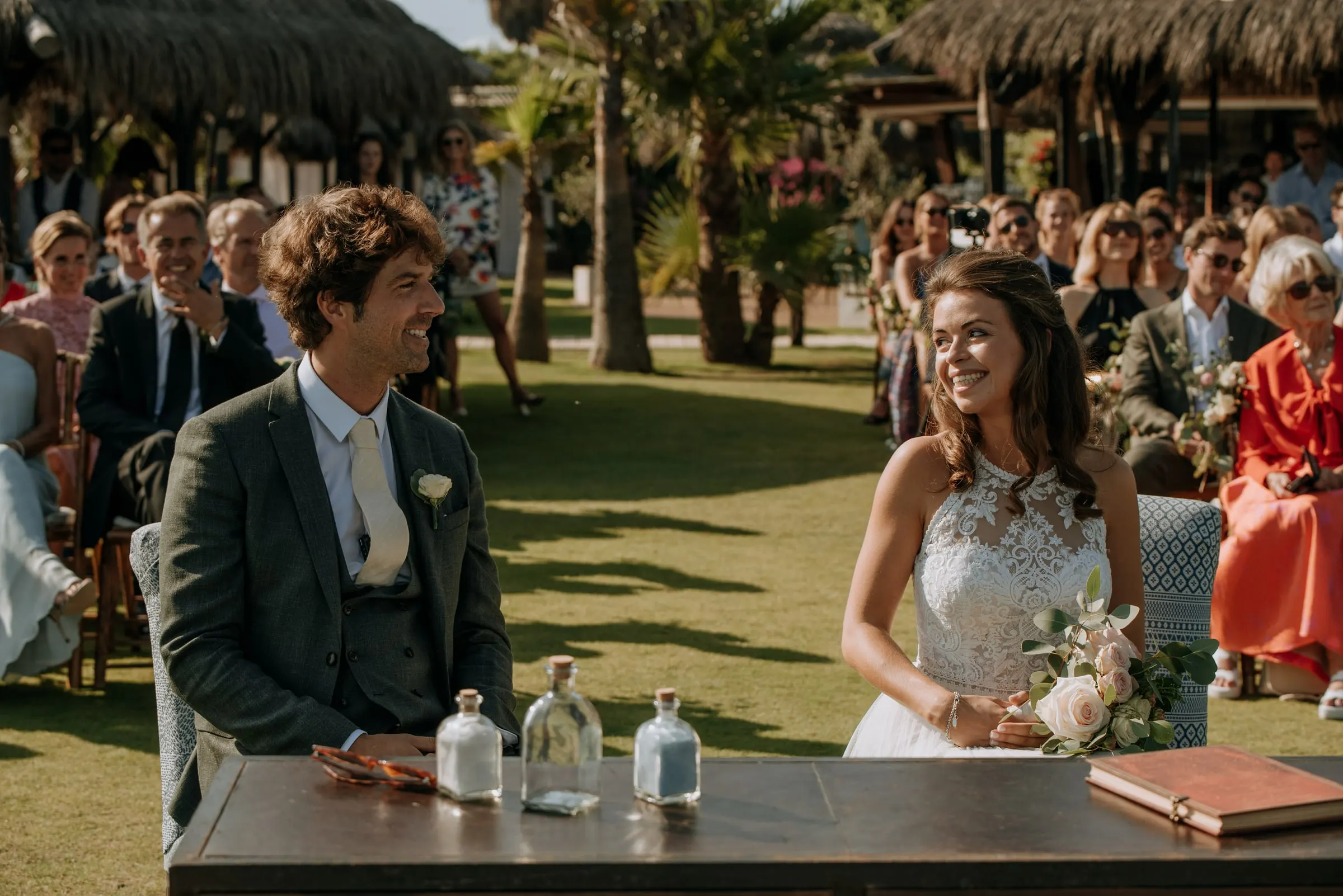 Bride and groom seated at the ceremony table, sharing a smile, Trocadero, Sotogrande