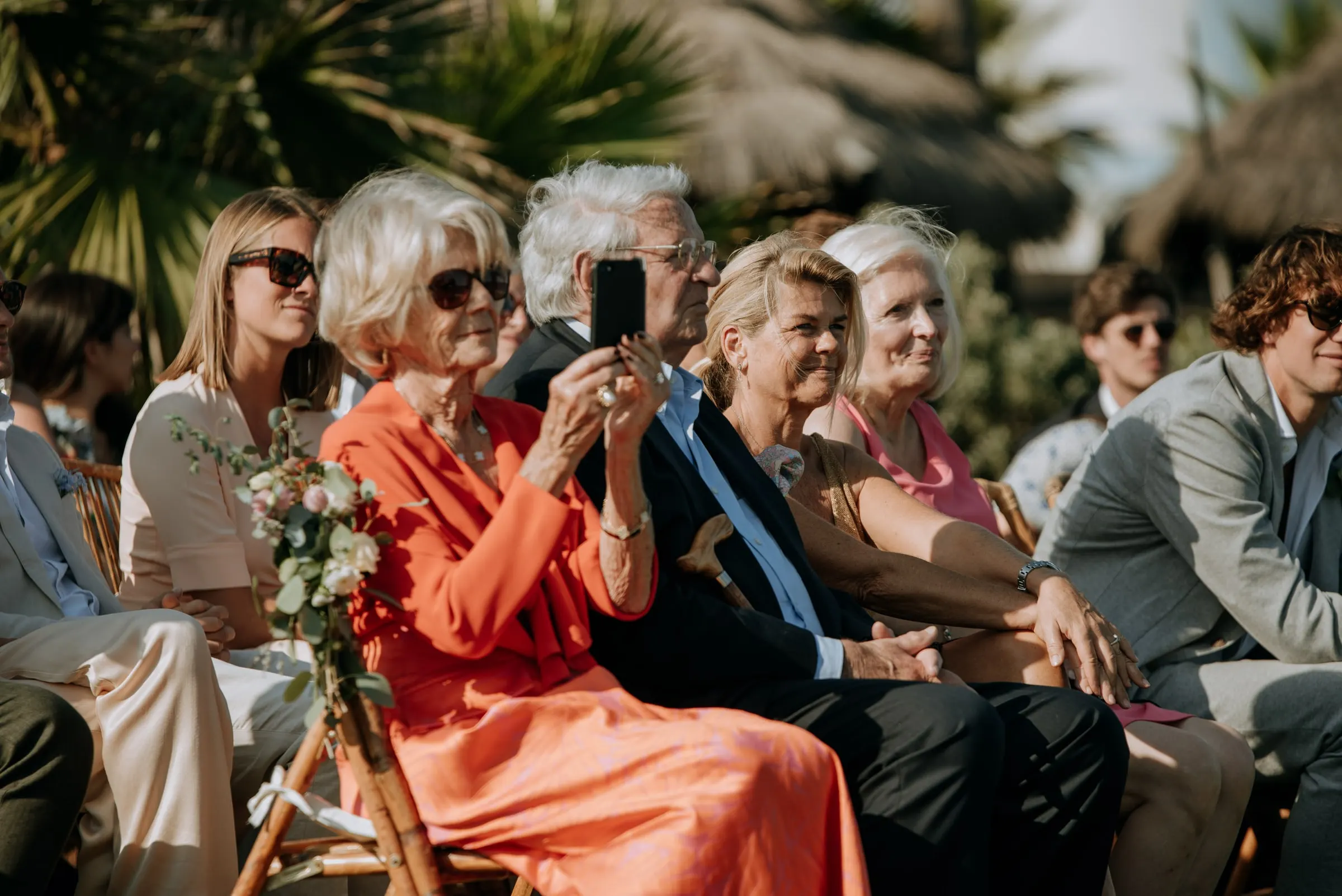 Guests in the front rows smiling, one filming the ceremony on her phone, Trocadero, Sotogrande