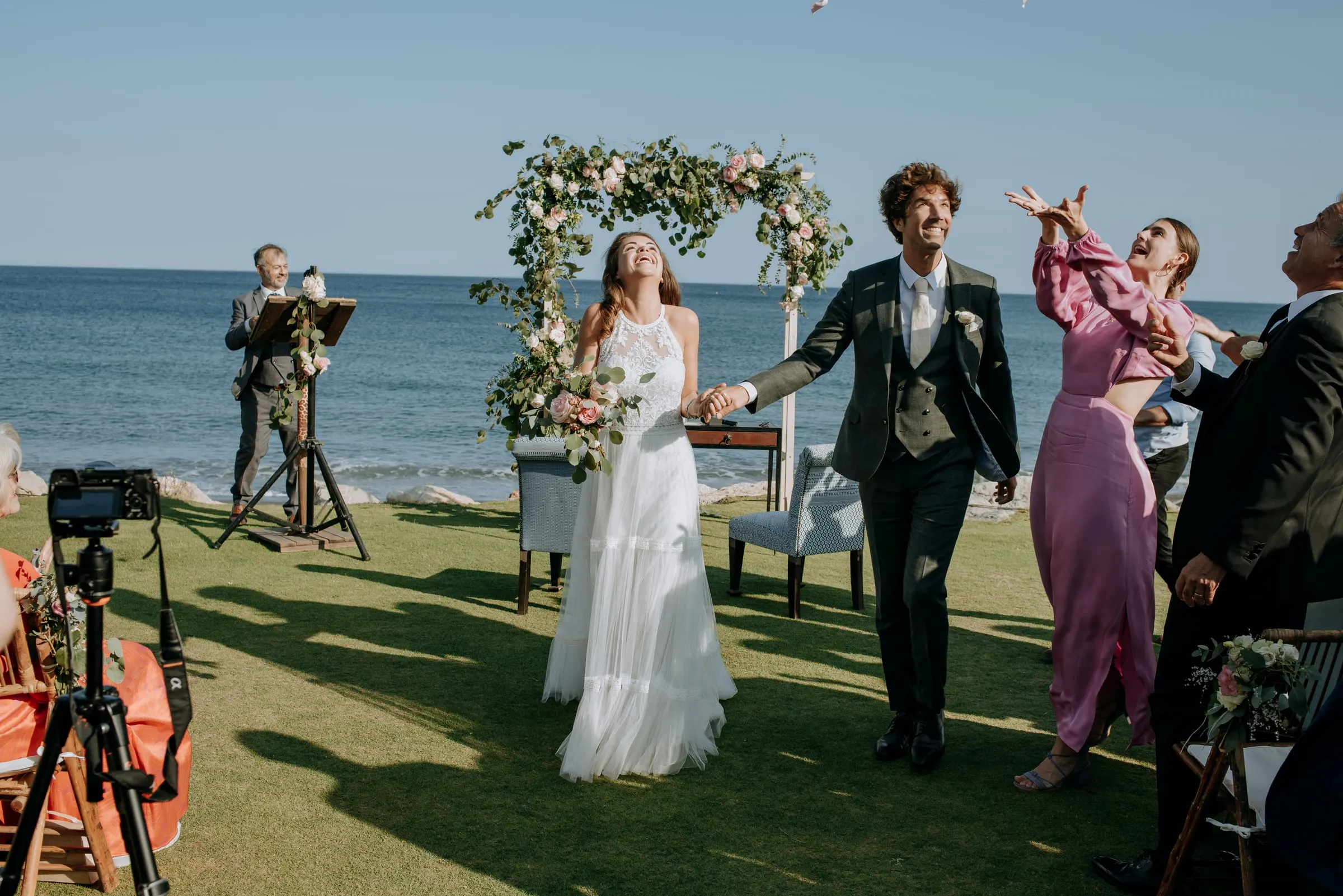 The newlyweds leaving the ceremony as a guest throws her arms up in joy, Trocadero, Sotogrande
