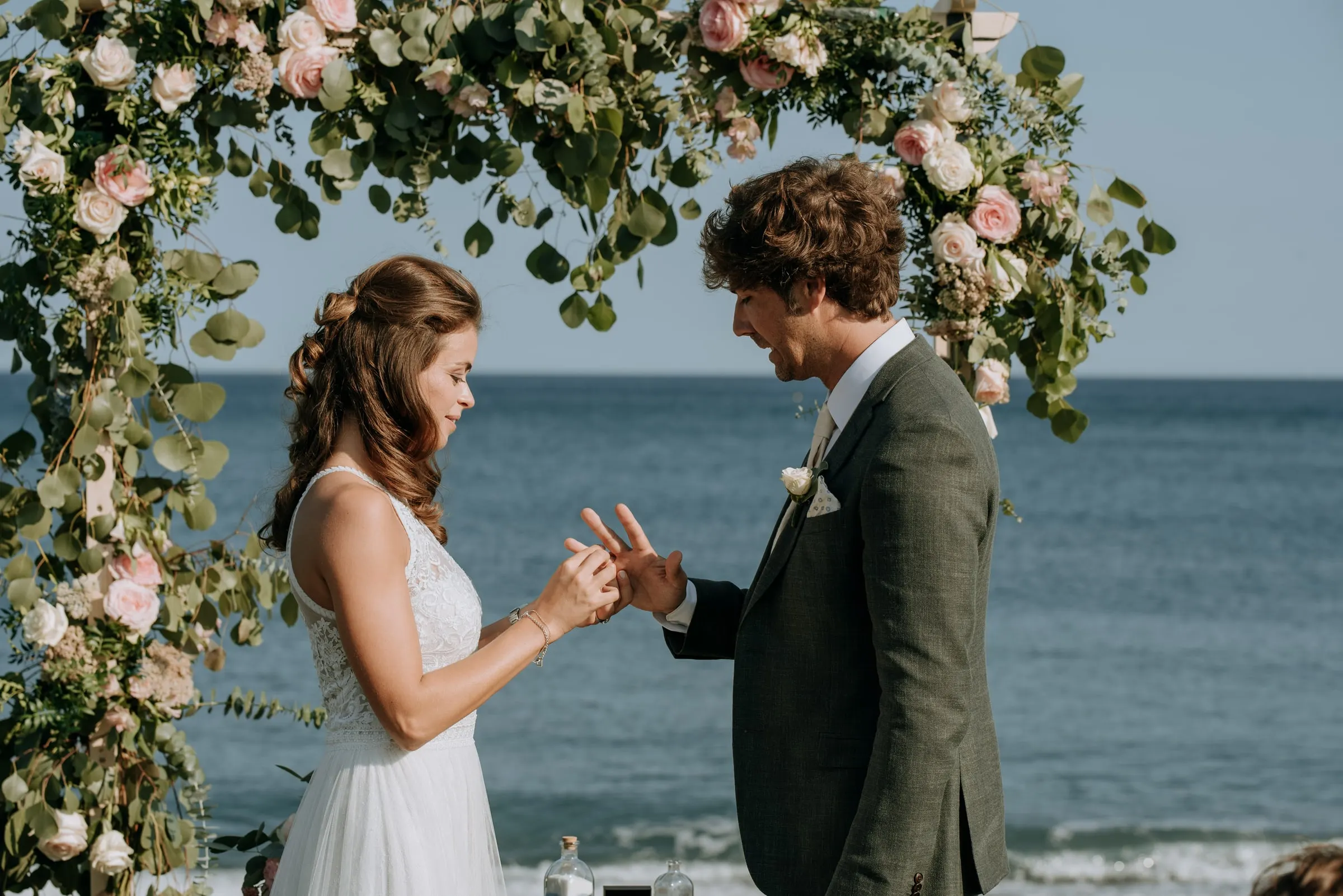 The bride placing the ring on the groom's finger under the flower arch, Trocadero, Sotogrande