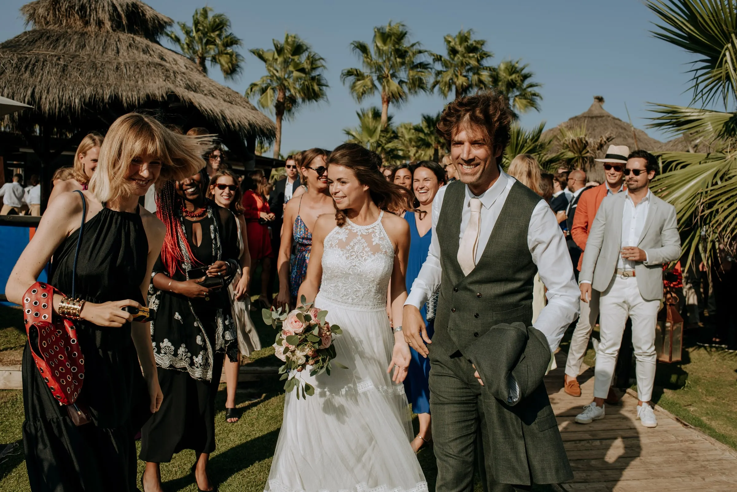 Bride and groom walking through the guests along a path lined with palms, Trocadero, Sotogrande