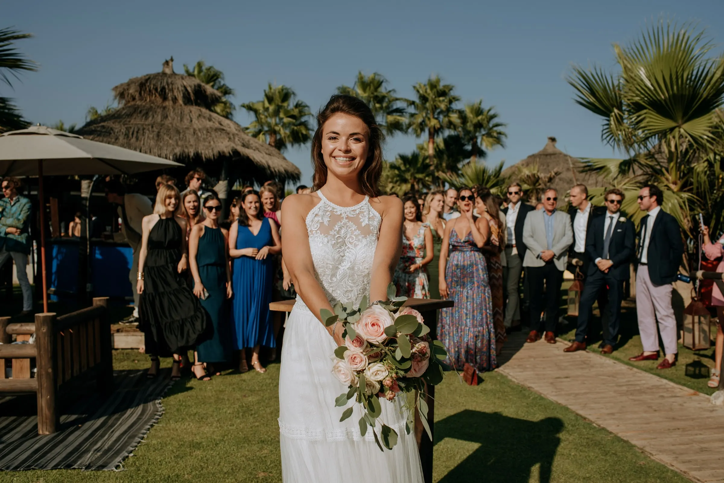The bride smiling with her bouquet before the toss, guests waiting behind, Trocadero, Sotogrande