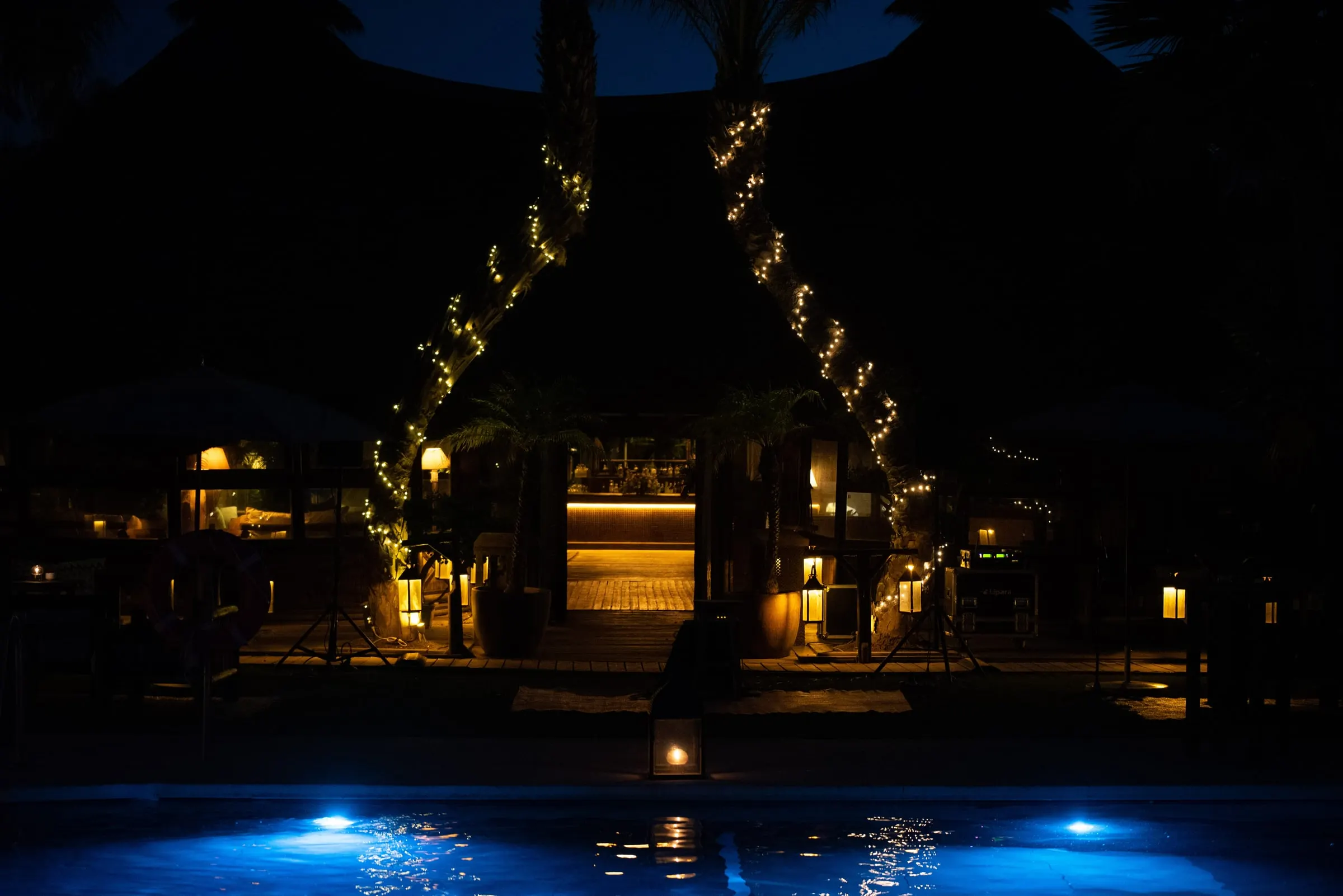 The pool lit blue at night with fairy lights strung between the palms, Trocadero, Sotogrande