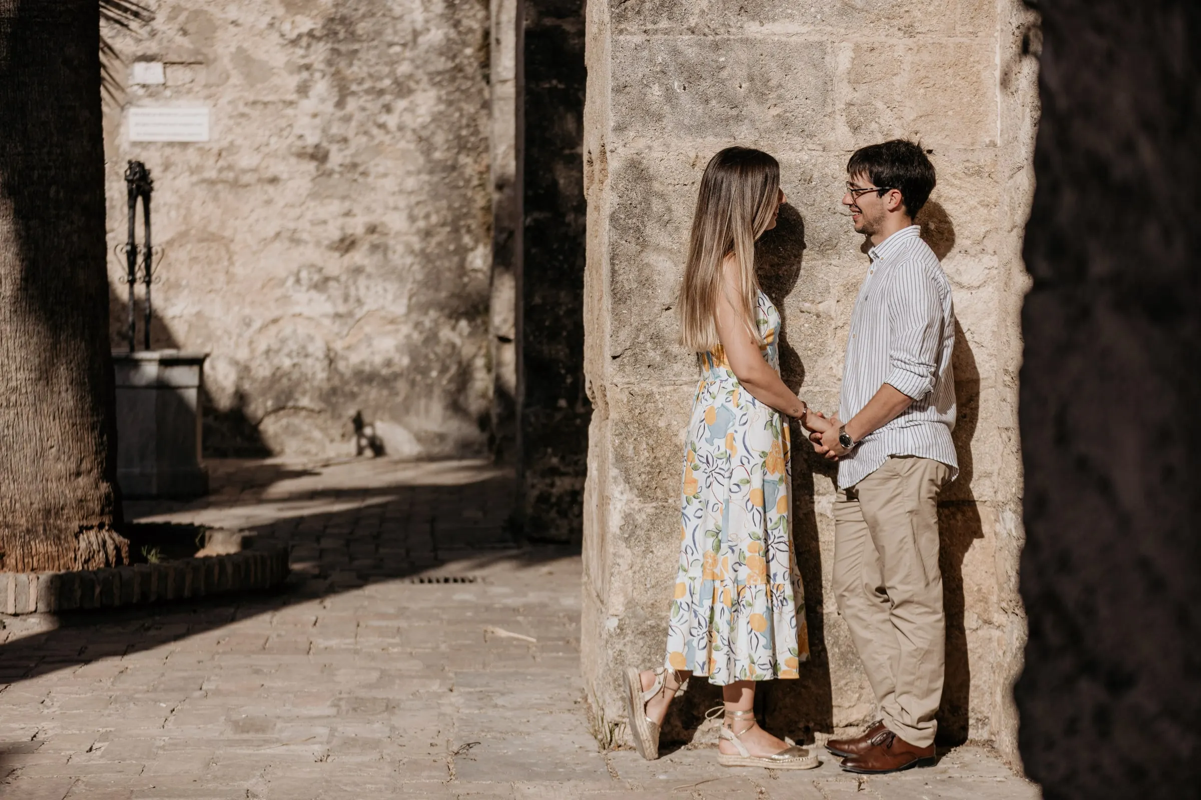 Pareja de la mano bajo un arco de piedra del casco antiguo de Vejer de la Frontera, sesión preboda