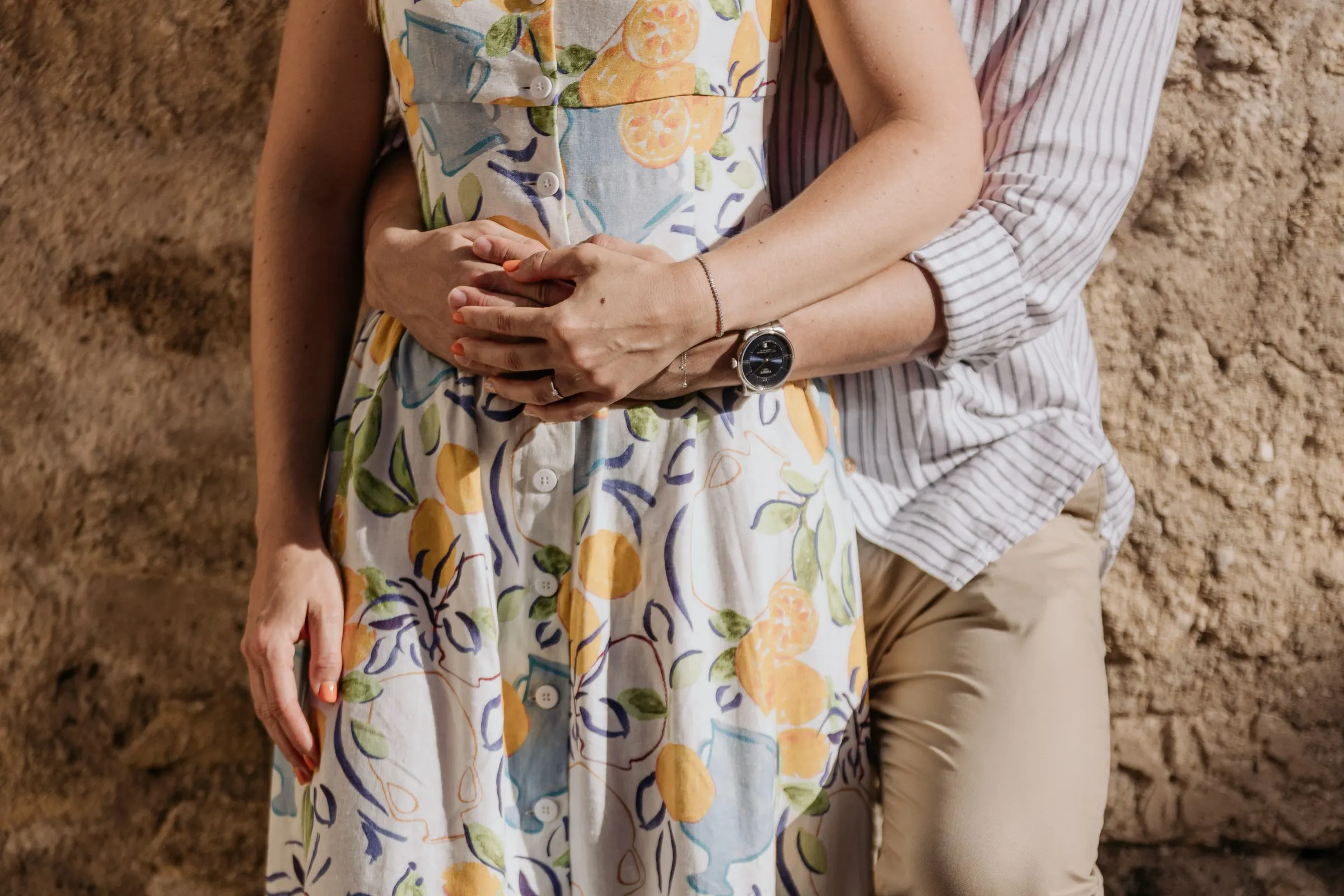 Detalle de sus manos en la cintura sobre el vestido de flores, sesión preboda en Andalucía