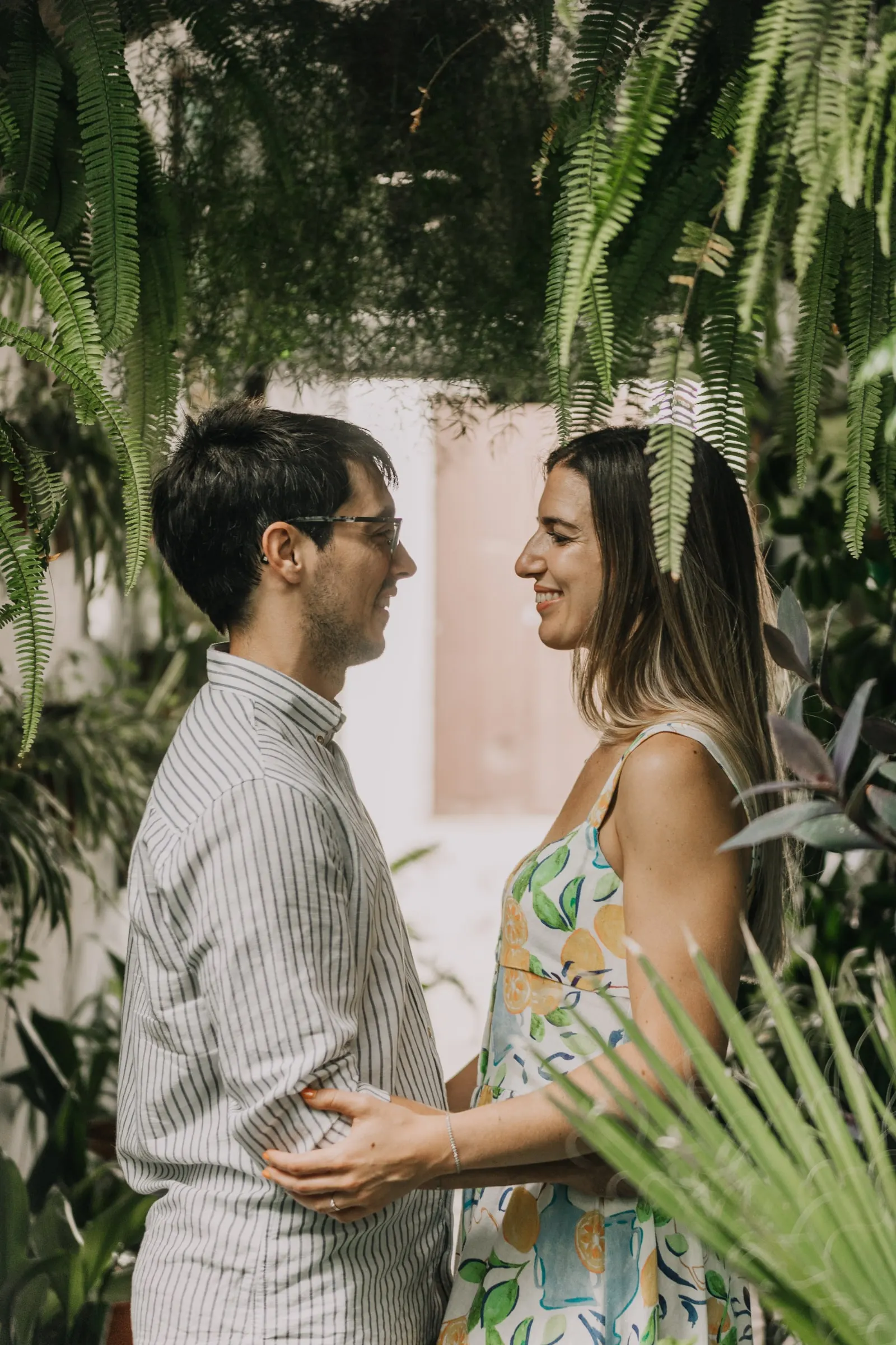 La pareja se sonríe entre plantas tropicales en un patio de Vejer