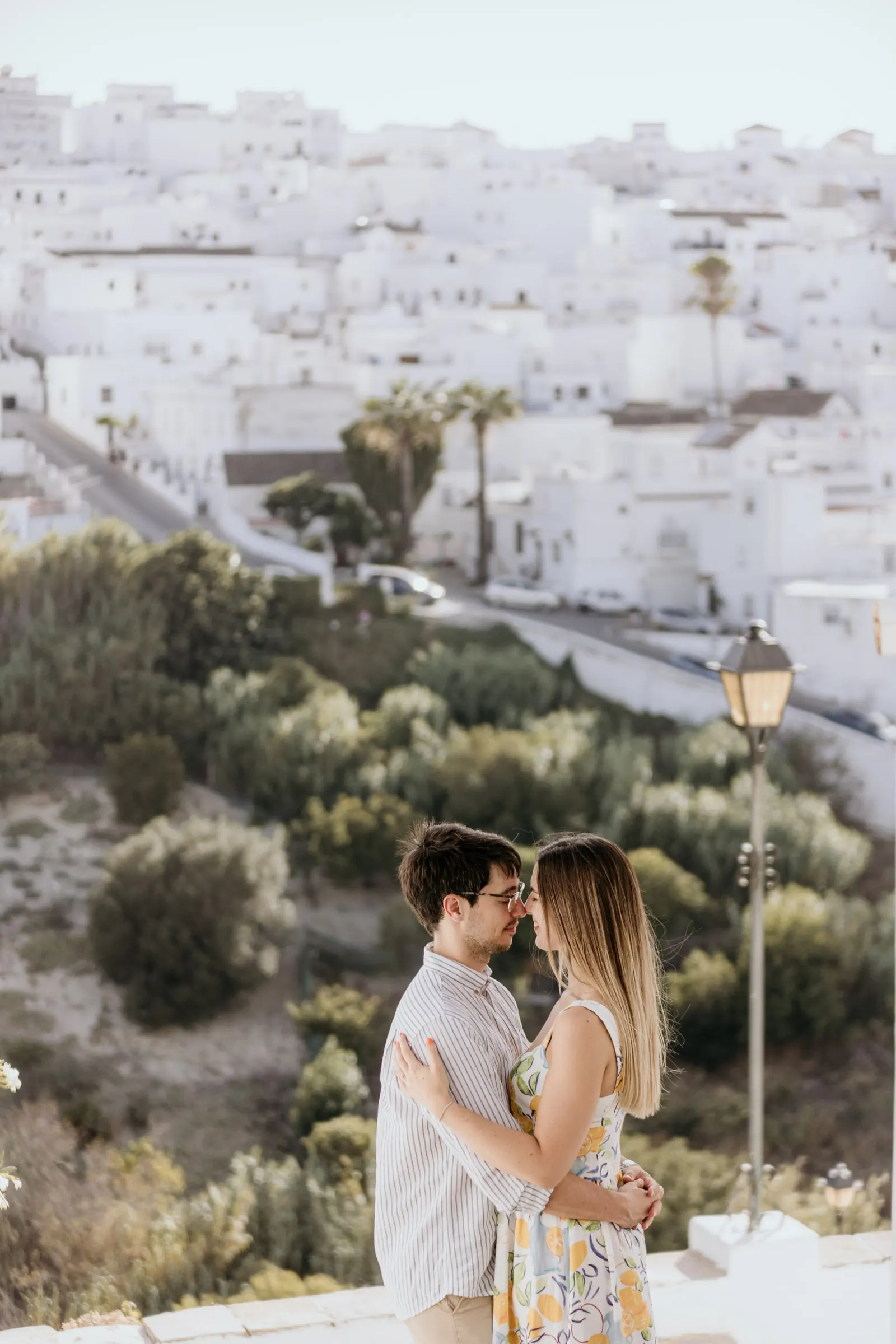 La pareja abrazada junto a una farola sobre las casas blancas y la ladera de Vejer de la Frontera
