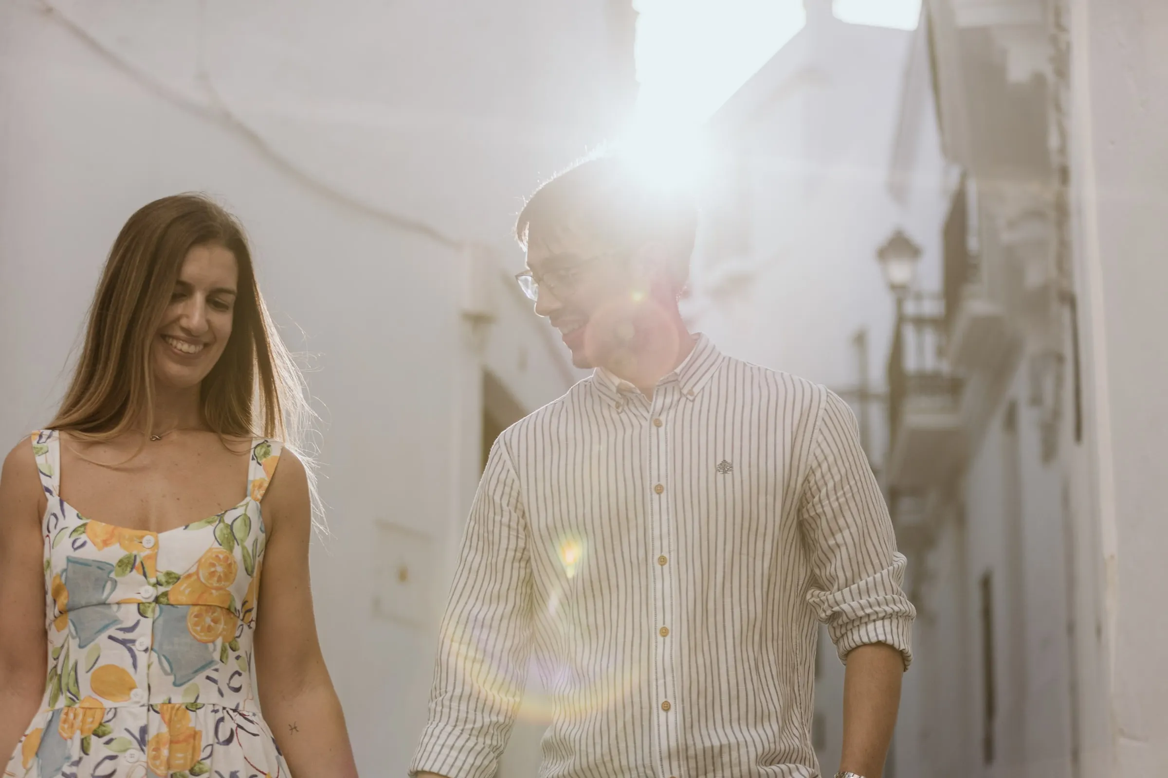 La pareja camina de la mano con el sol destellando entre las casas blancas de Vejer