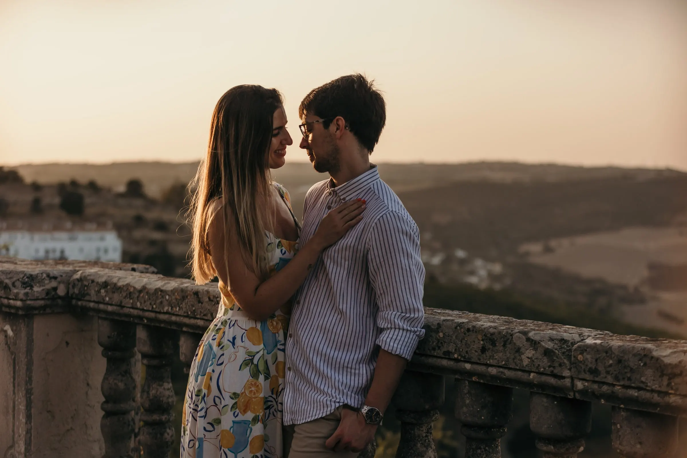 La pareja a punto de besarse junto a la balaustrada del mirador en la hora dorada, Vejer de la Frontera