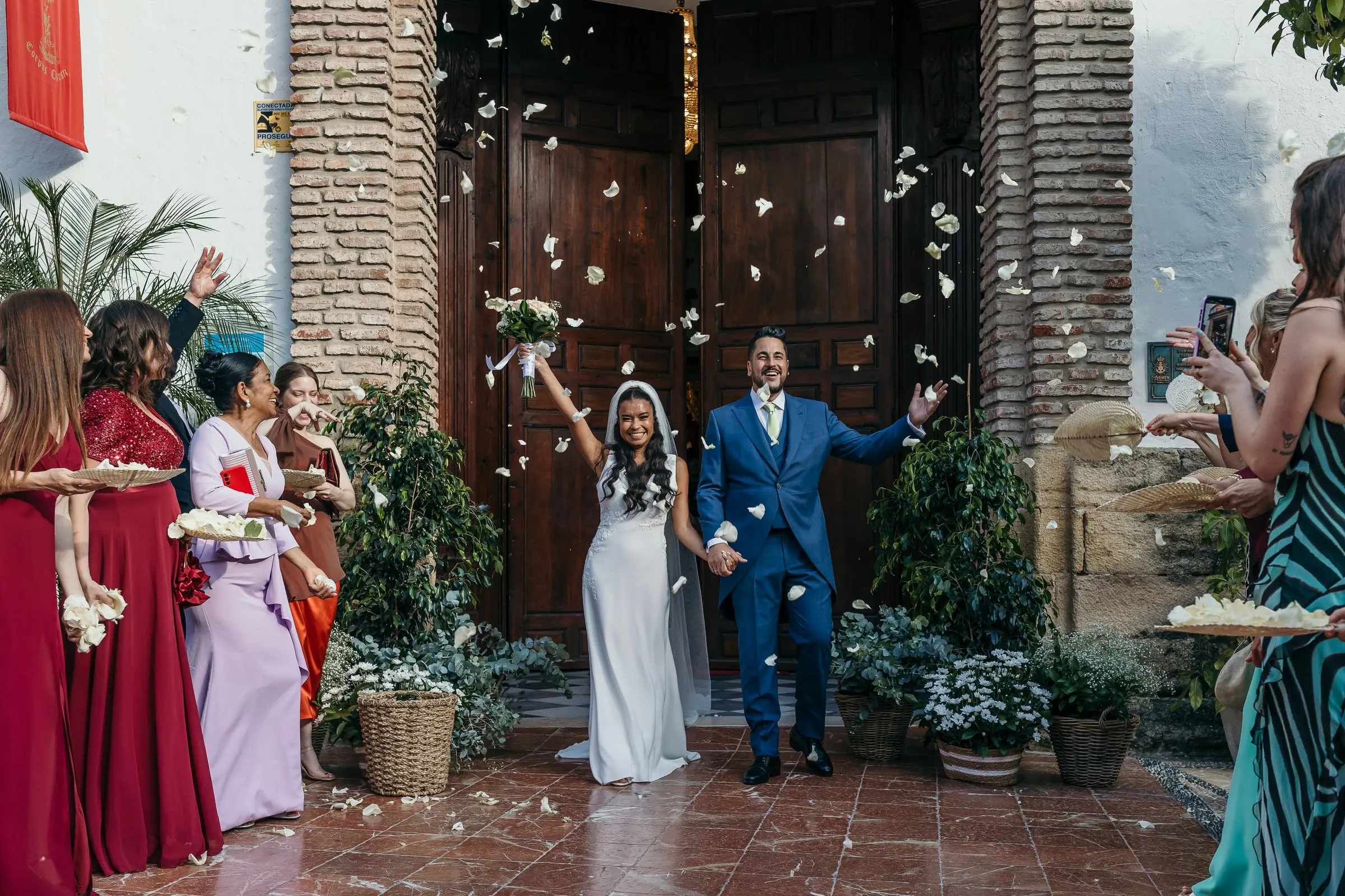 Newlyweds walking out of the church through a shower of white petals, Marbella