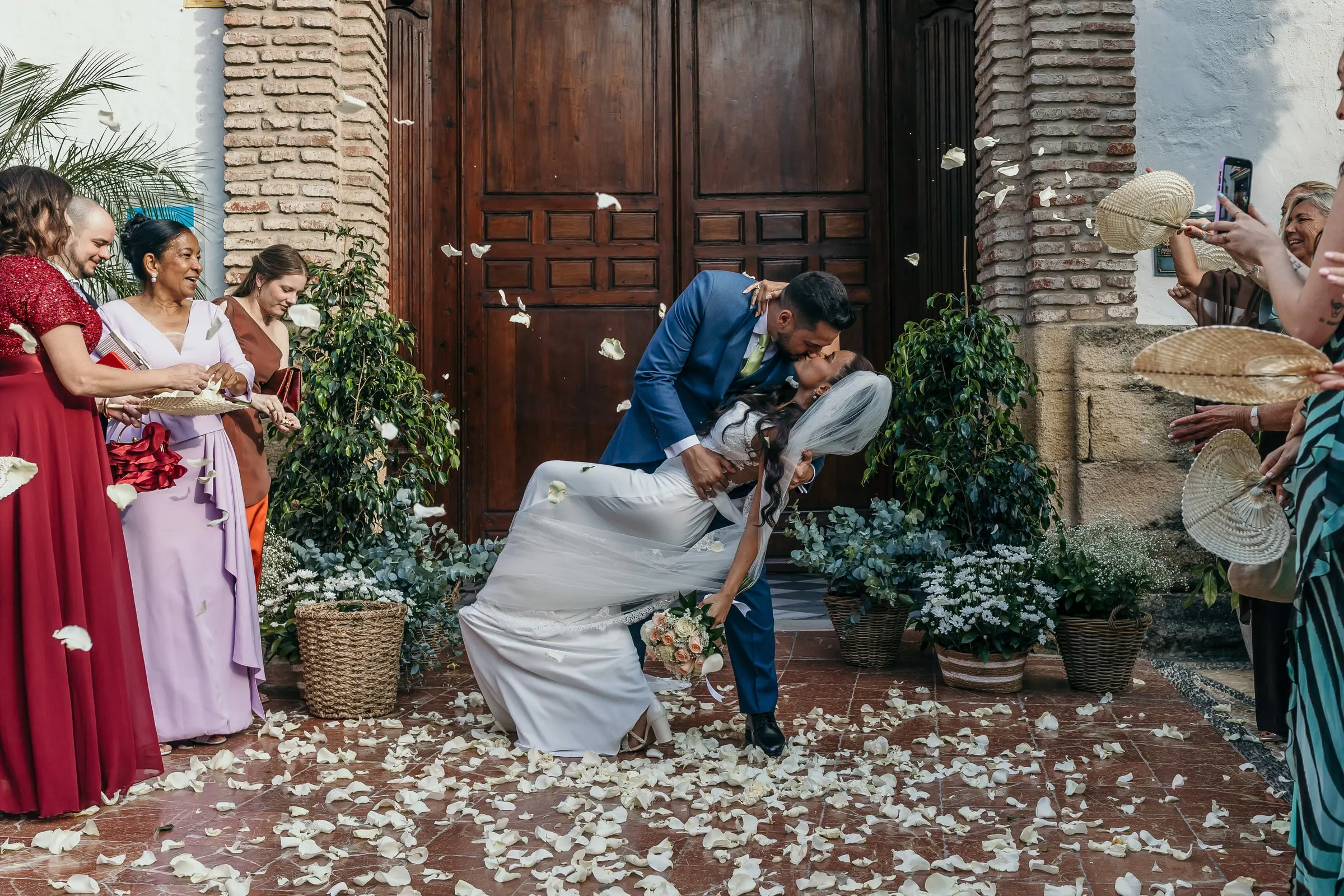 Groom dipping the bride for a kiss on the petal-covered church steps