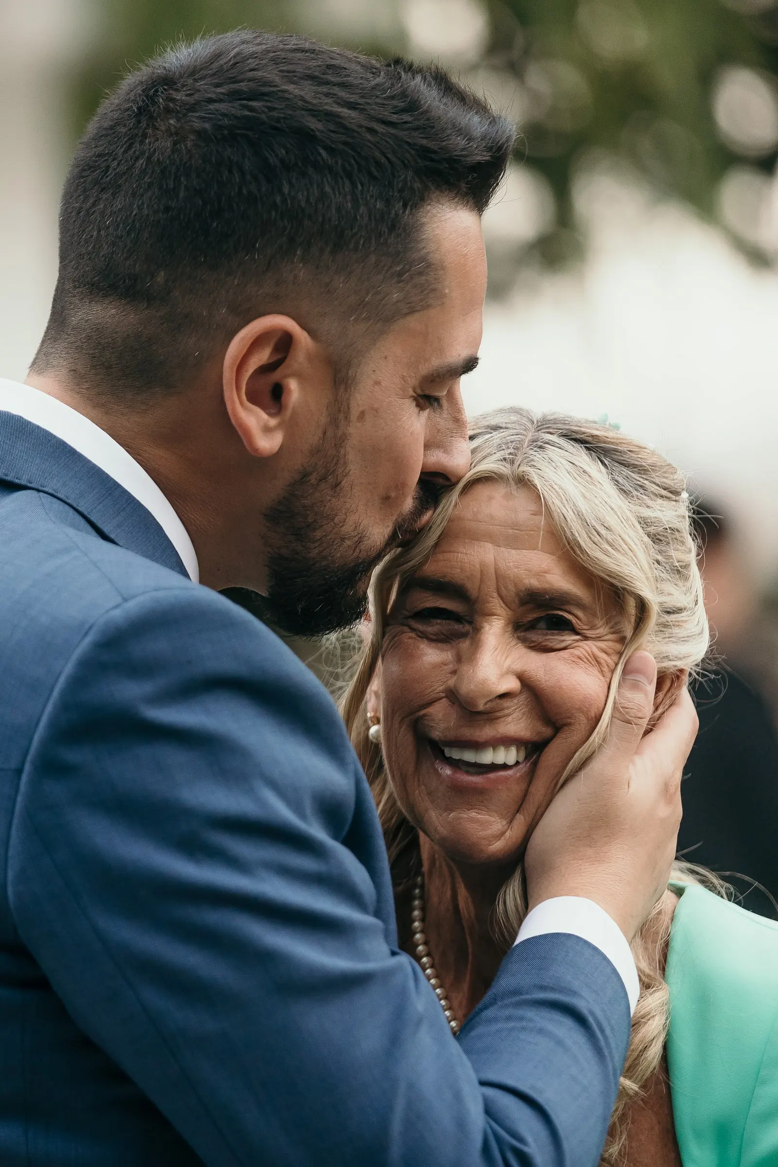 Groom kissing his mother on the forehead as she holds his face, Marbella wedding