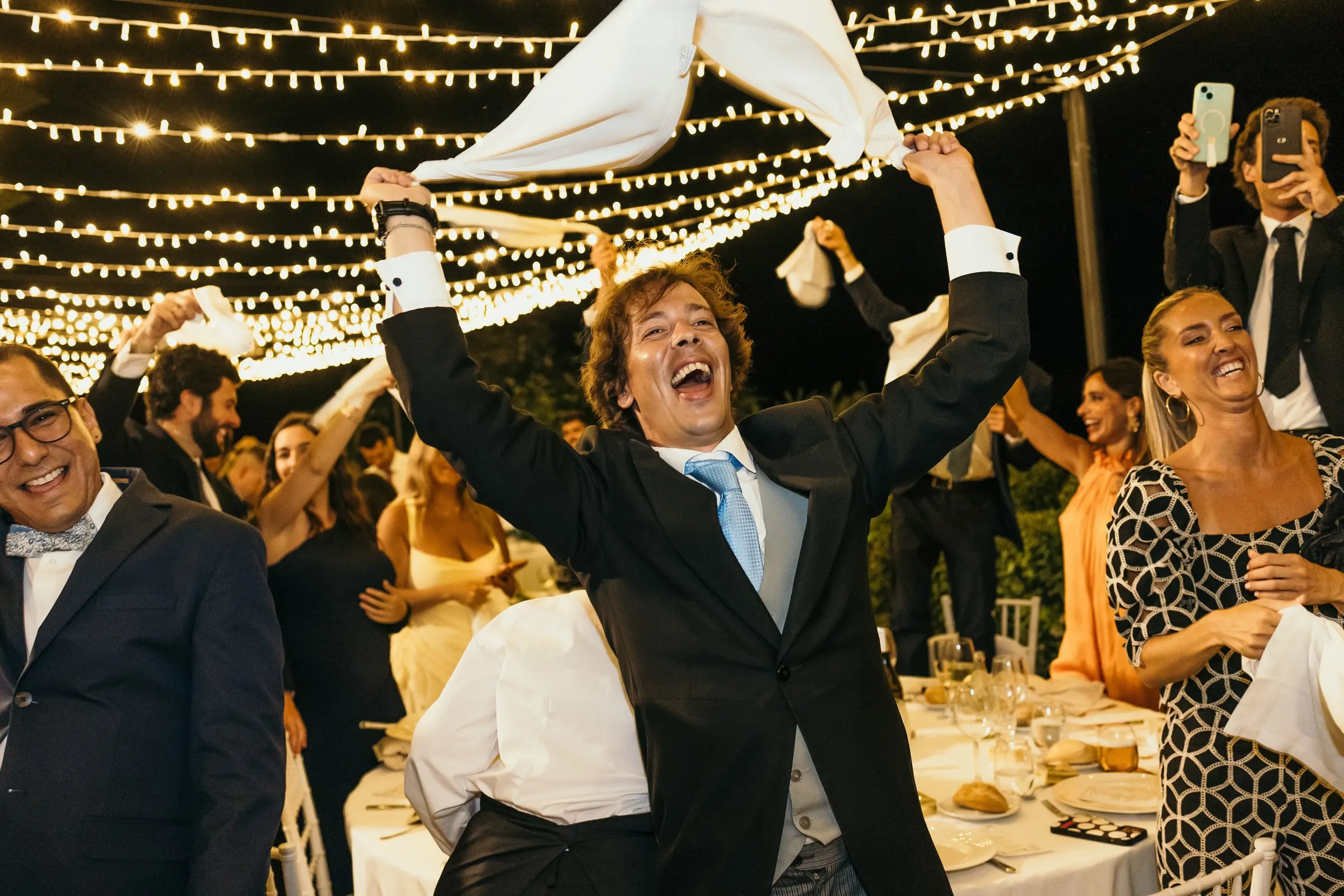 Guest jumping and twirling a napkin between the tables under the lights