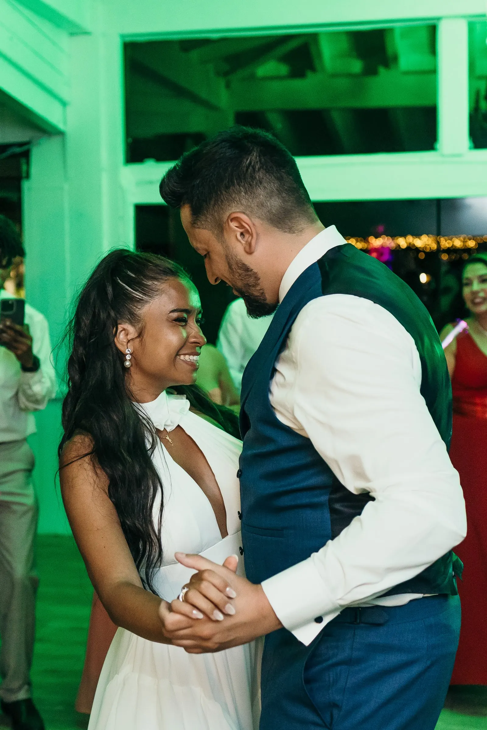 Couple dancing close under green light at the Marbella wedding party